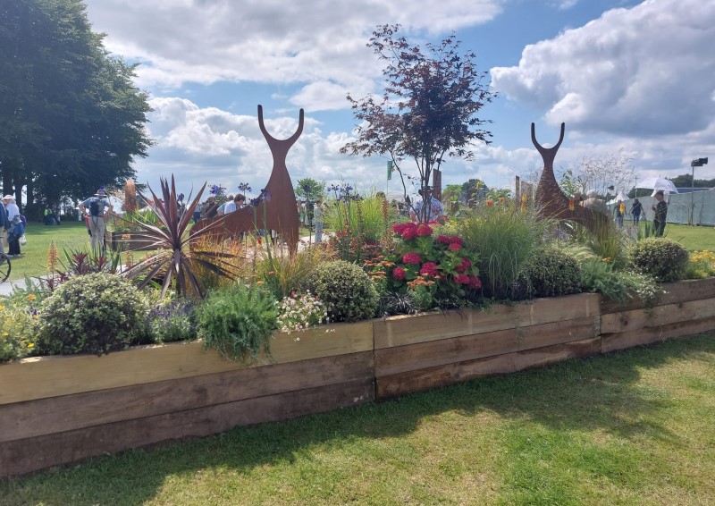 model deer in a garden exhibit of flowers and trees in a field